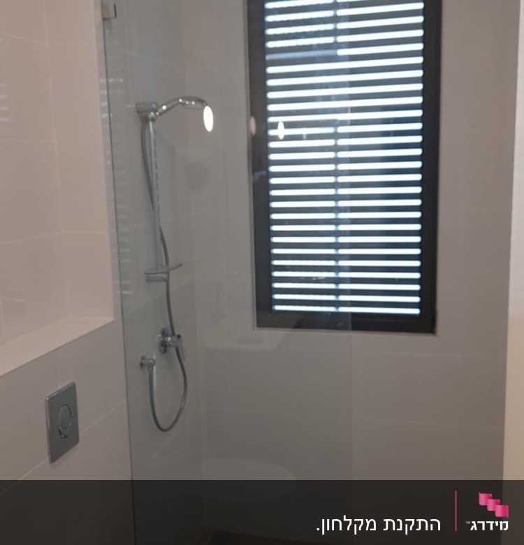 מקלחת עם ראש מקלחת וכיור ליד חלון